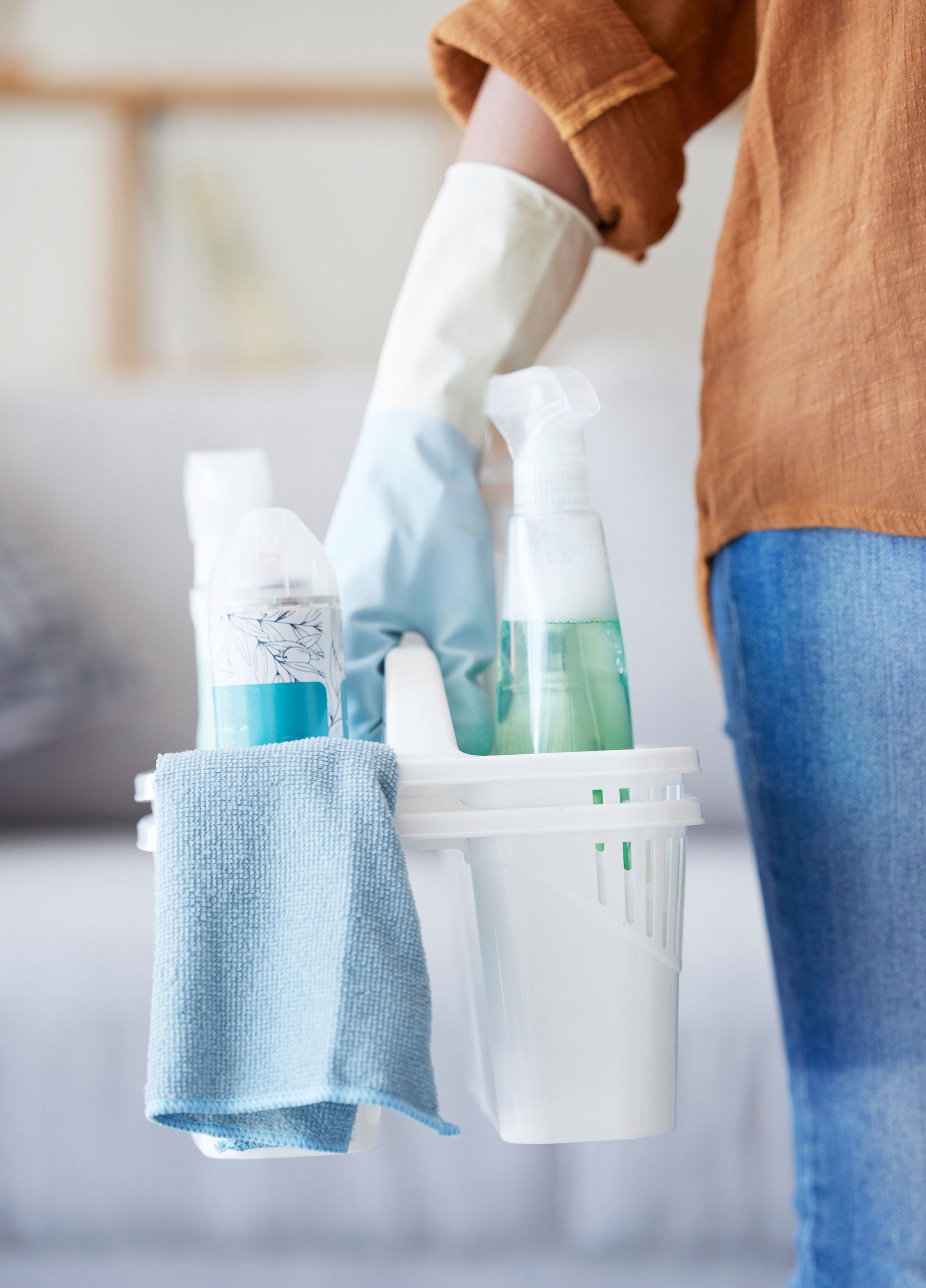 Hands, cleaning detergent and spray bottle, container and cleaning service for bacteria, glove and product in home. Cleaner, basket and housekeeper working, service and chemical in house with woman